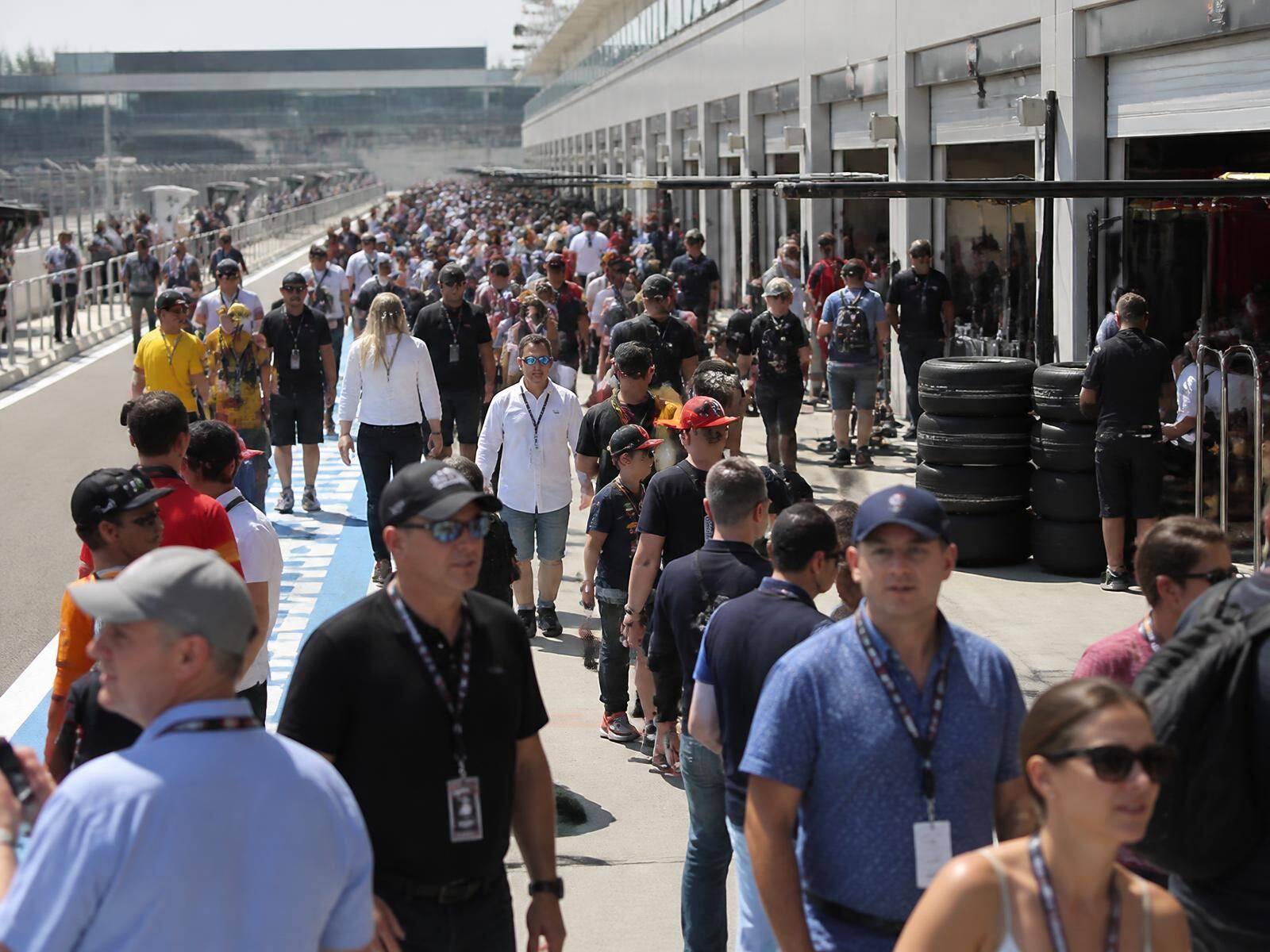 Bezoekers lopen tijdens de Pitlane Walk over de pitstraat langs de open garages